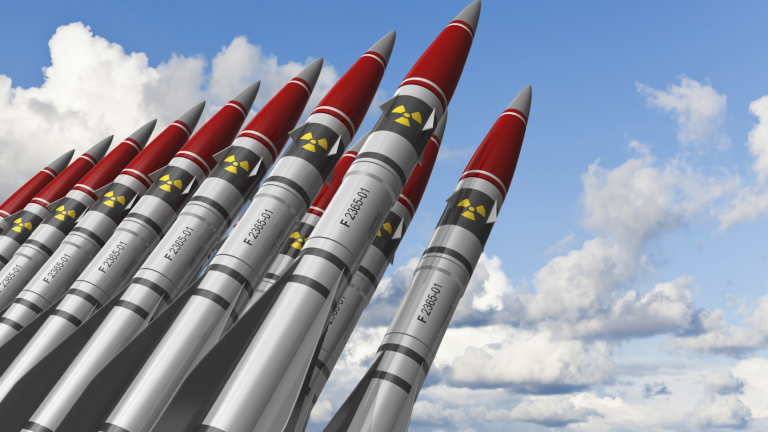 Row of heavy nuclear missiles against blue sky with clouds