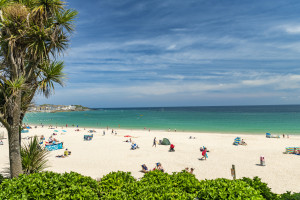Porthminster Beach, St. Ives, Cornwall on a busy saturday in June. The weather is hot and sunny, the beach full on people enjoying their day. Views towards St. Ives Town.